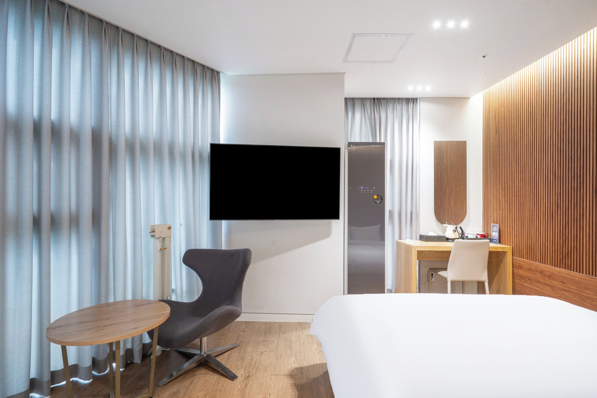 Een hotelkamer met een bed, een bureau, een stoel, een televisie en een kledingkast.
