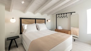 Un dormitorio con cama, mesitas de noche, una lámpara colgante y un espejo.