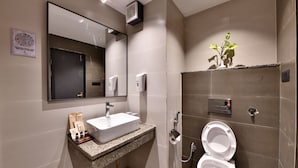 Un baño moderno con lavamanos de granito, un espejo, un inodoro y un secador de manos en la pared.