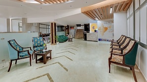 Un vestíbulo amplio con muebles modernos, una recepción y una escalera que lleva a los pisos superiores.