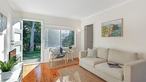 Una sala moderna con un sofá, una mesita y un sillón. Un ventanal grande ofrece vistas al exterior.