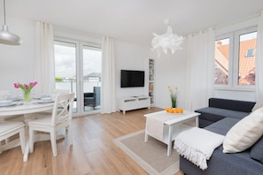 Ein modernes Wohnzimmer mit Essbereich, einem Flachbildfernseher und einer Couch.