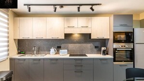 Eine moderne Küche mit grauen Schränken, einem eingebauten Backofen und einer Kaffeemaschine.