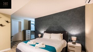 Ein modernes Schlafzimmer mit einem großen Bett, Nachttischen, einem Kleiderschrank und einer Wand in dunkler Farbe.