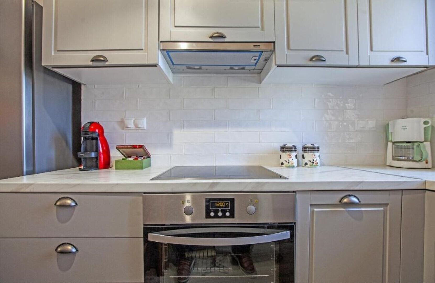 A modern kitchen with stainless steel appliances, a built-in oven, and a coffee maker.