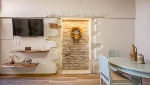 Une pièce avec un mur en briques, une étagère en bois, une table et une chaise.