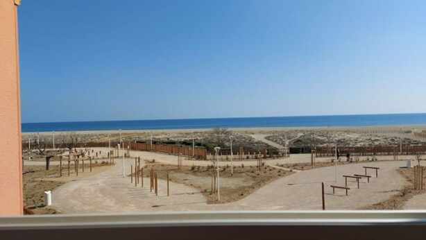 A view of a beach area with pathways and a fence, leading to the sea. - Logement Front de mer à Port Leucate (Leucate)