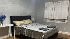 Ein Schlafzimmer mit Bett, Nachttisch, Lampe und einem Sessel.