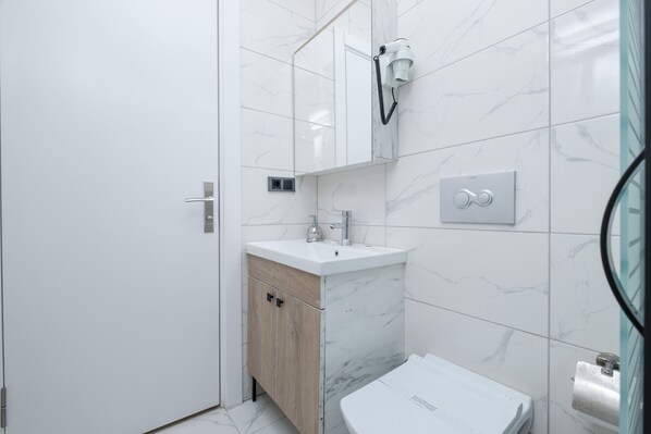 Un baño moderno con un lavamanos blanco, un mueble de madera y un inodoro.