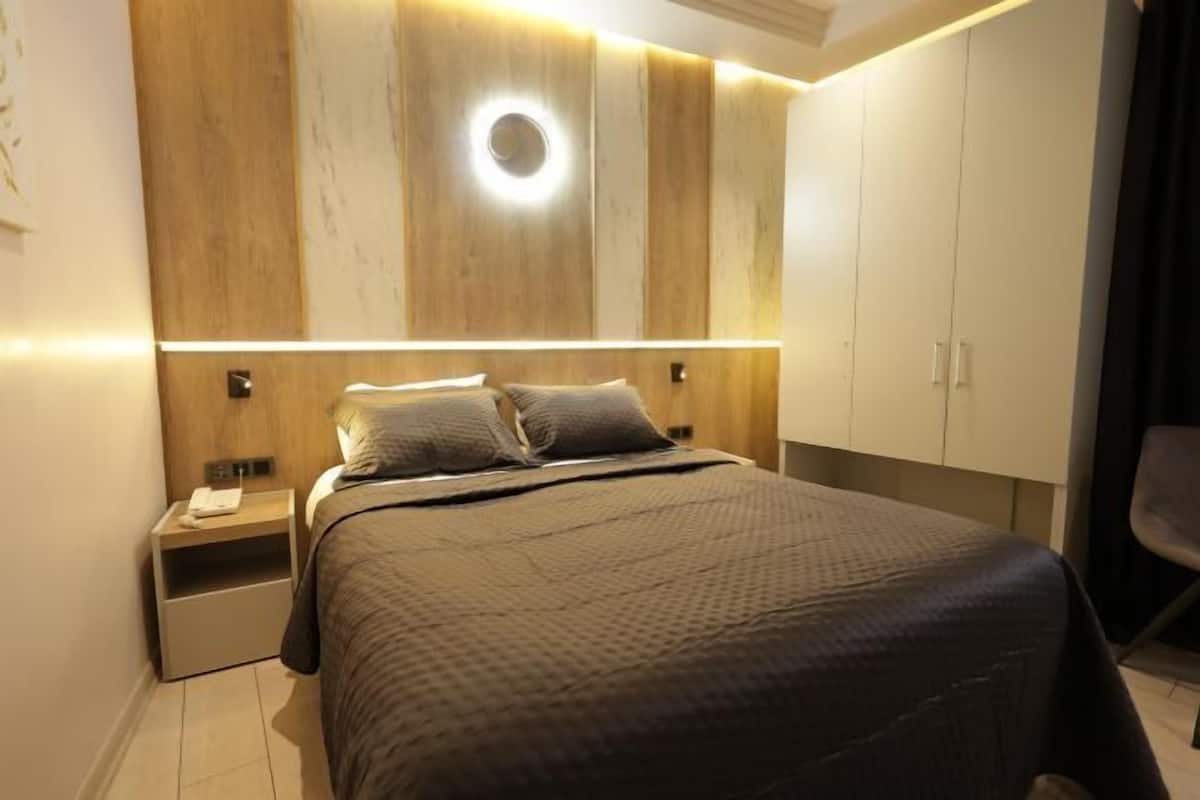 A bedroom with a bed, nightstands, a wardrobe, and a circular light fixture on the wall.