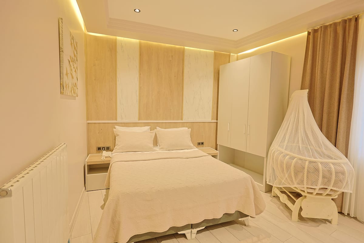 Une chambre à coucher comprenant un lit, des tables de chevet, une armoire et une moustiquaire.