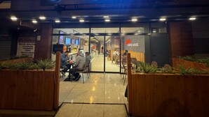 Gloria Jean's Coffee House with a neon sign, outdoor seating, and a visible menu board. - Lavender Airport Hotel (Arnavutköy)