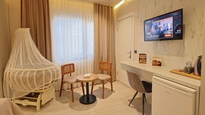 A hotel room with a bed, a TV mounted on the wall, a dining table with chairs, and a small kitchenette. - Lavender Airport Hotel (Arnavutköy)