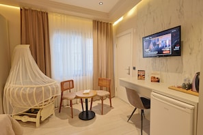 Une chambre d’hôtel comprenant un lit, un téléviseur fixé au mur, une table à manger avec des chaises et une petite kitchenette.