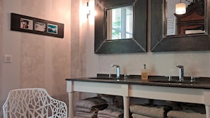 A bathroom with a large mirror, two sinks, and a towel rack.