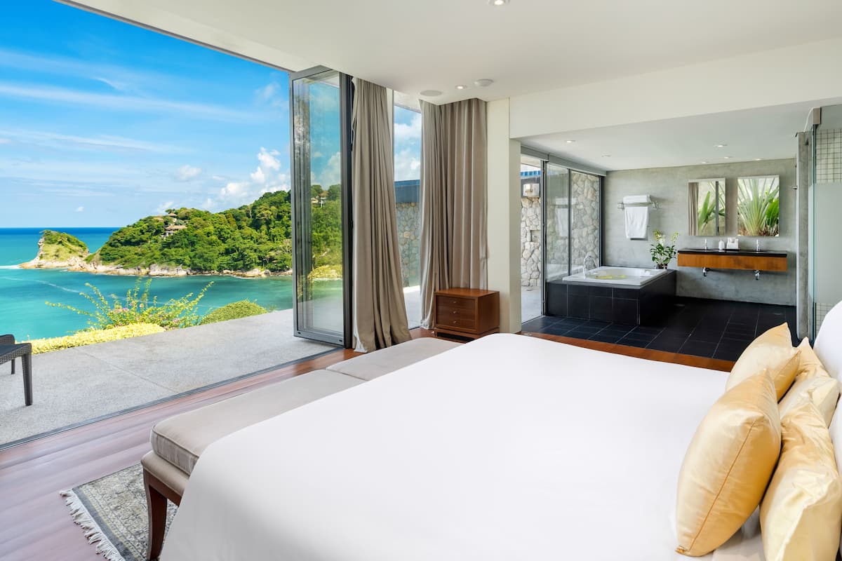 Un dormitorio con una cama grande, un baño con bañera y vistas al océano.
