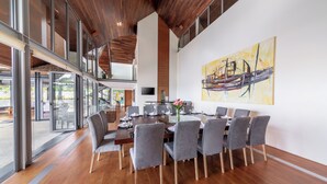 Un'area pranzo moderna con un tavolo grande, sedie grigie e un soffitto in legno.