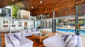 Un'ampia zona giorno con piscina, arredi moderni e soffitto in legno.