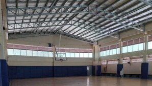 Una palestra da basket al coperto con soffitto alto e ampie finestre.