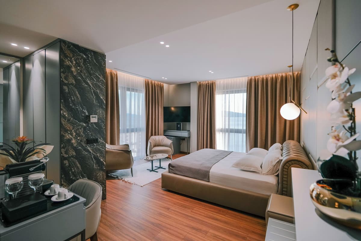 Ein modernes Hotelzimmer mit einem großen Bett, einem Schreibtisch, einem Sessel und einem Fernseher.