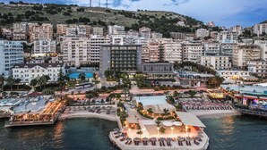 A coastal hotel with multiple buildings, a pool, and a beach area with sun loungers.
