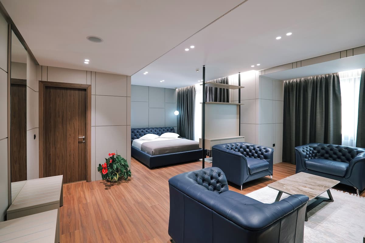 Ein modernes Schlafzimmer mit einem großen Bett, zwei Sesseln, einem kleinen Tisch und Holzboden.