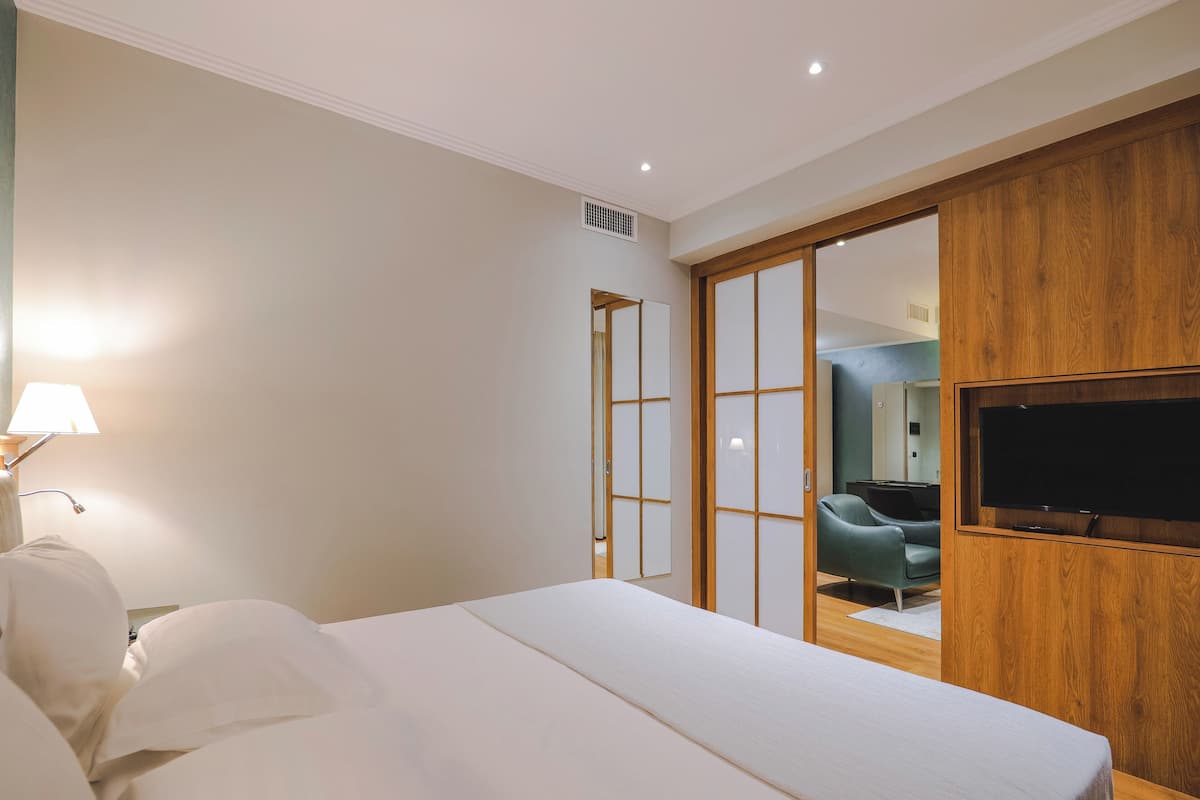 Ein Hotelzimmer mit einem Bett, einem Fernseher, einem Holzschrank und einem Spiegel.