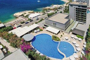 Vista aérea de un hotel con una gran piscina, zona de descanso en la playa y vistas al océano.