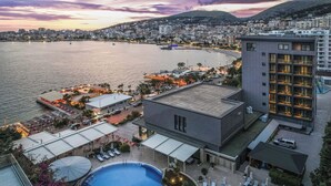 A hotel with a pool, outdoor seating, and a view of the sea.