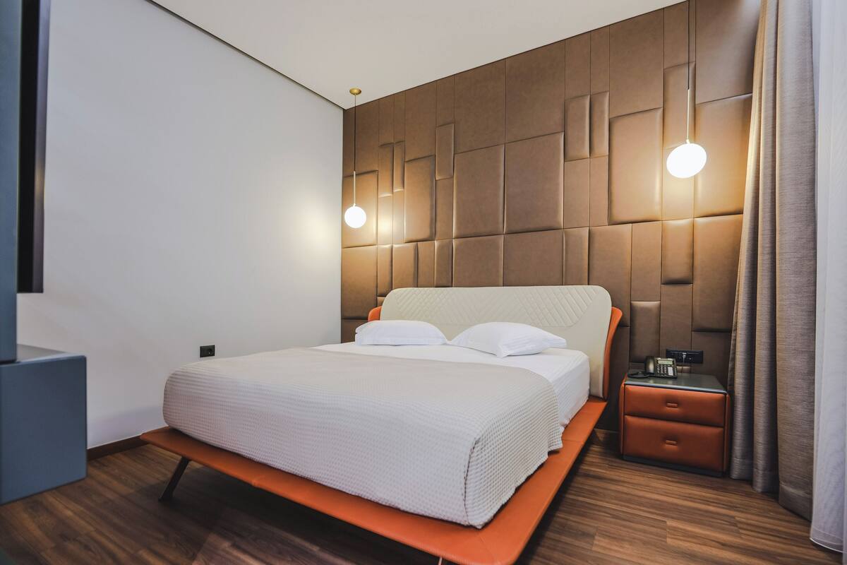 Ein modernes Hotelzimmer mit einem großen Bett, einem Nachttisch und einer Wandleuchte.
