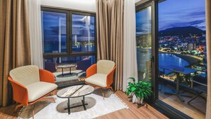 A balcony with a city view, two armchairs, a small table, and a potted plant.