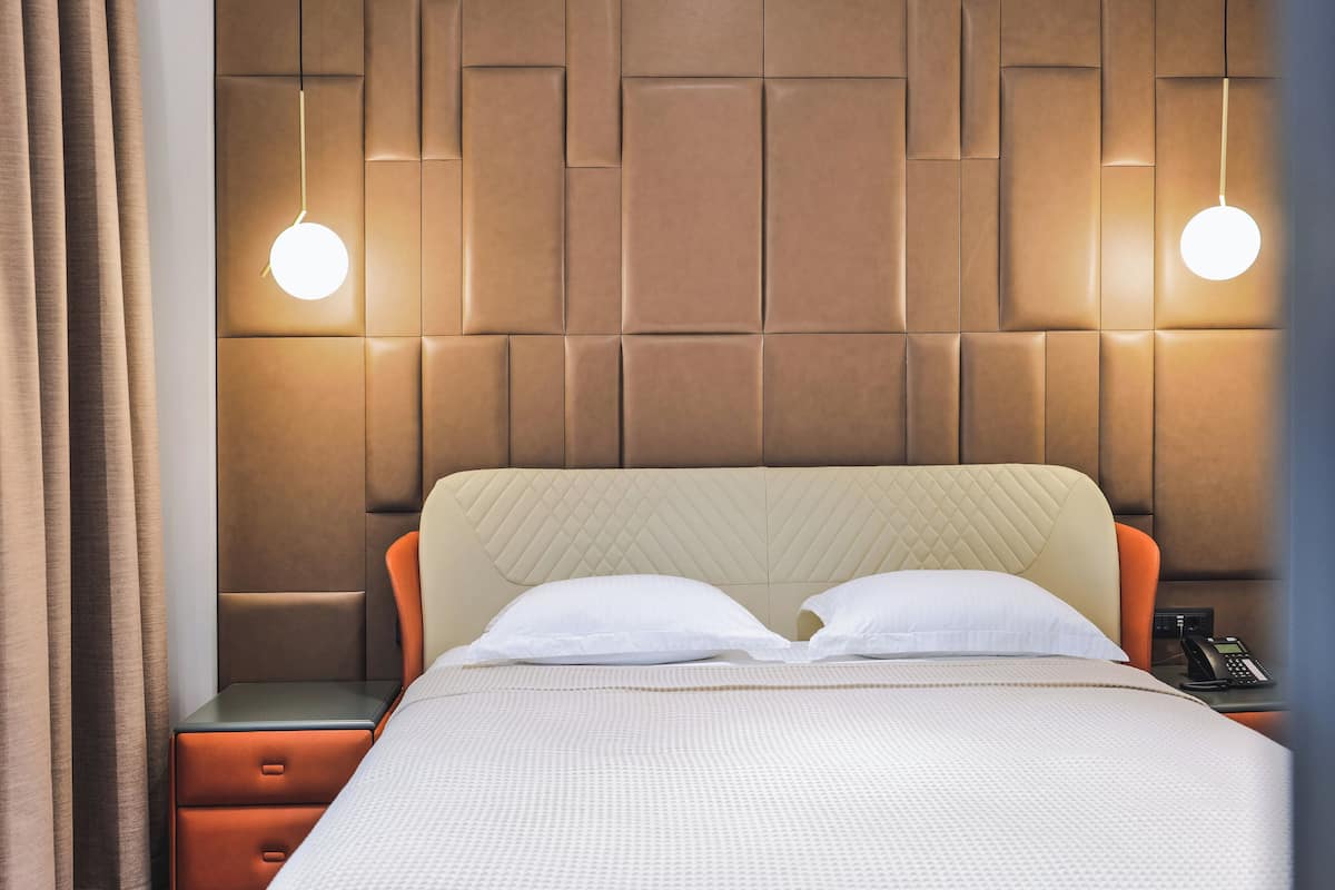 Ein Hotelzimmer mit einem großen Bett, einem Nachttisch, einem Telefon und einer Wandleuchte.