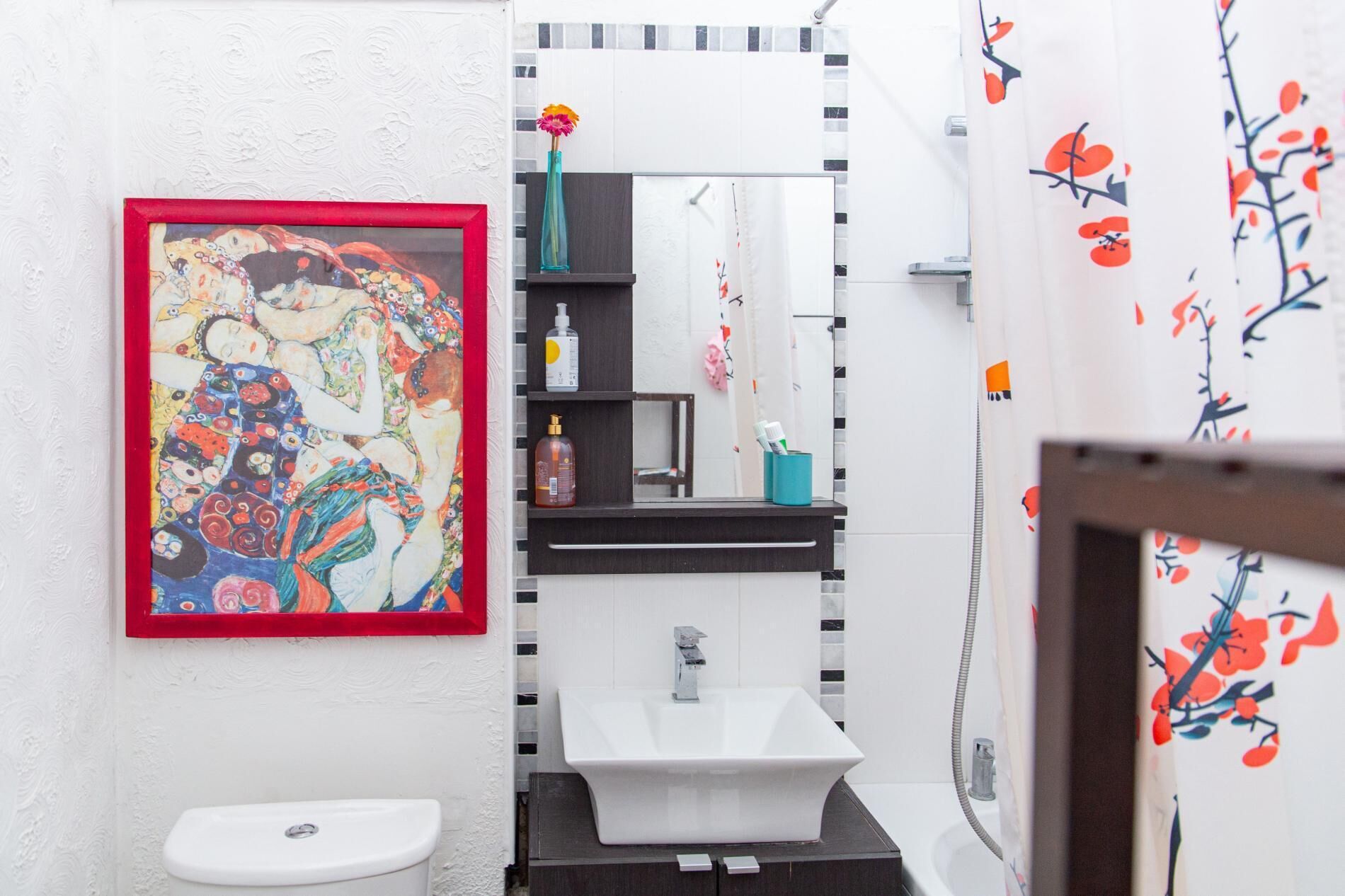 Un bagno con un lavandino bianco, uno specchio e un quadro appeso alla parete.
