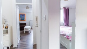 Ein Schlafzimmer mit einem Bett, einem Nachttisch und einer Kommode. Eine Tür führt in einen anderen Raum.