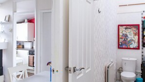 Ein helles Interieur mit Esstisch und Stühlen, einer weißen Toilette und einem Heizkörper.