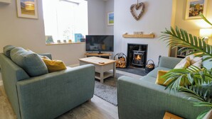 A living room with two green sofas, a TV, a fireplace, and a heart-shaped decoration on the wall. - Y Bwthyn (Llanbedr)