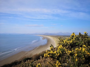 A coastal landscape with a beach and distant mountains. - Y Bwthyn (Llanbedr)