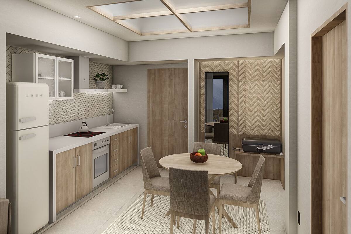A compact kitchen with a built-in refrigerator, a kettle, and a sink. There is a dining area with a round table and four chairs.