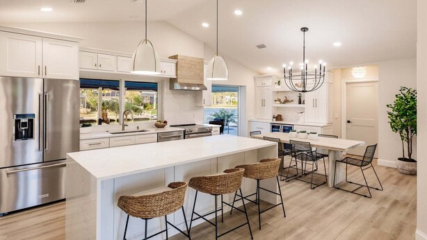 A modern kitchen with a large island, stainless steel appliances, and a dining area with bar stools.