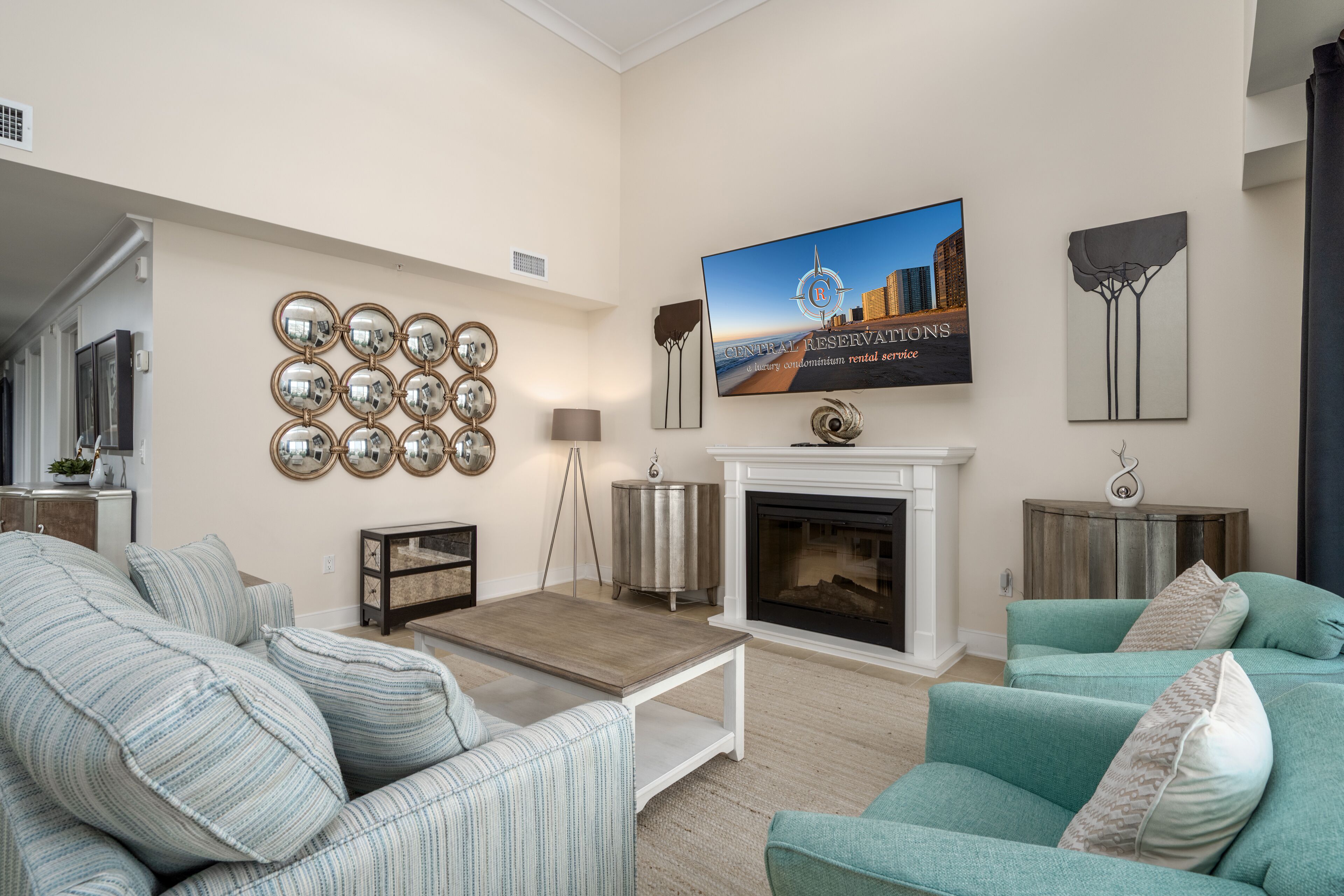 A living room with a fireplace, a television mounted above it, and a wall decorated with circular mirrors and a painting.