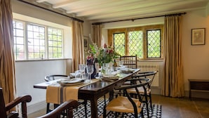 Ein Esszimmer mit einem Holztisch, gedeckt für vier Personen, umgeben von Stühlen, mit einem Blumenstrauß und Weinflaschen auf dem Tisch.