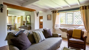 Ein gemütliches Wohnzimmer mit Sofa, Sessel und einem fenster mit Vorhängen.