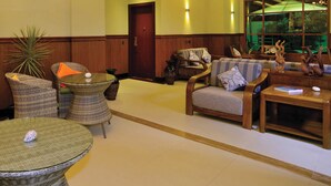 Eine großzügige Lobby mit hoher Decke, eleganten Kronleuchtern und einer komfortablen Sitzecke mit Sofas und Sesseln.