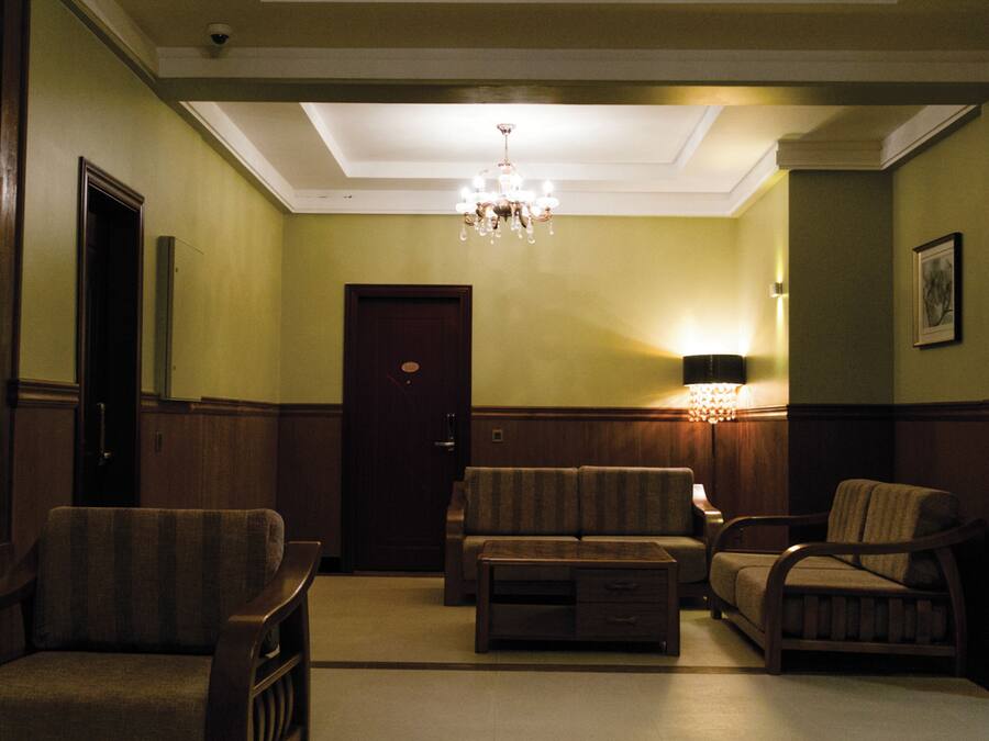 Una sala elegante con candelabro, sofá, sillones y una puerta.