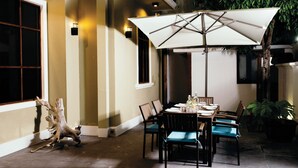 Eine Außenpatio mit Esstisch, Stühlen und einem großen Sonnenschirm.