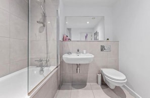 A modern bathroom with a glass shower enclosure, a white sink, and a toilet.