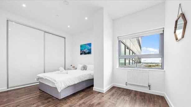 A bedroom with a bed, a large window, and a view of the outside. - Captivating 1-bed Apartment 15 min to Londonbridge (Croydon)