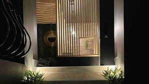A modern staircase leading to a room with a wooden floor and a view of a room with vertical blinds and a plant.