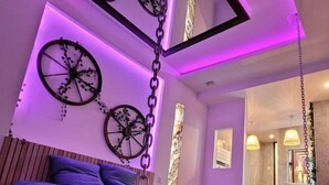 A bedroom with a bed suspended from the ceiling, wooden headboard, and wall-mounted wheels. - La Suite 2 Grenoble (Grenoble)
