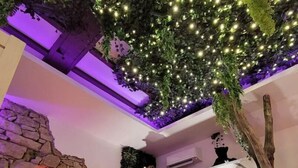 A hotel reception area with a stone wall, neon sign, and a ceiling with artificial greenery and lights. - La Suite 2 Grenoble (Grenoble)